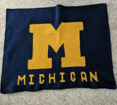 a crocheted blanket with the letter m on it and michigan written in yellow