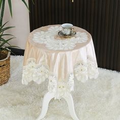 a table that has a cup and saucer on it with a plant in the background