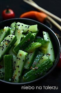 a bowl filled with cucumber and other vegetables next to some chopsticks