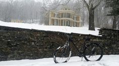 a bike parked next to a stone wall in the snow