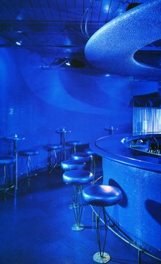 a dimly lit bar with blue lighting and stools