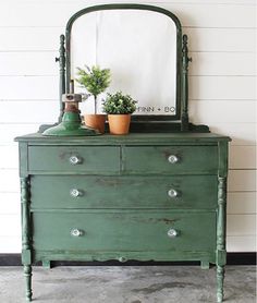 a green dresser with a mirror and potted plants on it's top shelf