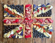 a cross made out of cheeses, meats and fruit on a wooden table