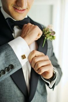 a man in a tuxedo adjusts his bow tie and boutonniere