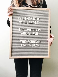 a woman holding up a sign that says let the king of my heart be the mountain where i run