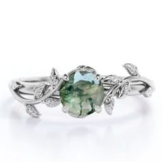 a green ring with leaves on the sides and a stone in the middle, surrounded by diamonds