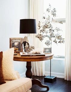 a living room filled with furniture and a lamp on top of a wooden table in front of a window