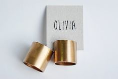 two rolls of gold colored tape sitting next to each other on a white surface with the word oliva printed on it