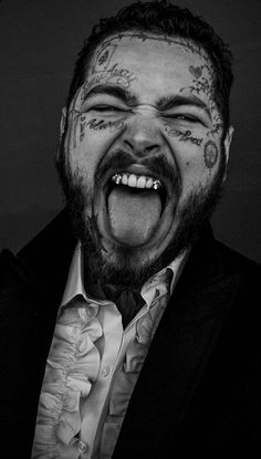 a man with tattoos on his face is making a funny face while wearing a suit