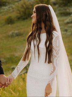 a bride and groom holding hands in a field