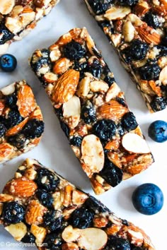 granola bars with blueberries and almonds on a white surface next to fresh blueberries