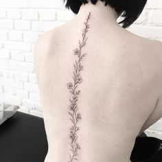 the back of a woman's neck with a flower tattoo on her left side