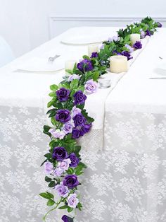 the table is decorated with purple flowers and greenery for an elegant touch to it