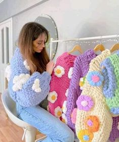 a woman sitting on a chair next to three crocheted purses with flowers