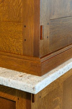 the corner of a wooden cabinet with marble top