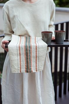 a woman holding a tray with two cups on it