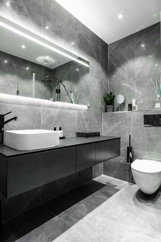 a modern bathroom with grey marble walls and flooring, along with a large white bowl sink