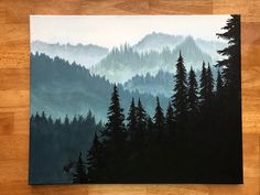 a painting of trees and mountains on a wooden surface with wood flooring in the foreground