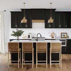 a kitchen with wooden floors and black cabinets is pictured in this image, there are four chairs at the center of the island