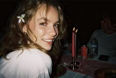 a woman sitting at a table with a candle in her hand