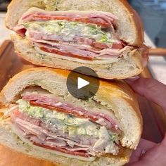 two halves of a sandwich with meat, cheese and lettuce on it being held by someone's hand