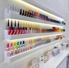 the shelves are filled with different colored nail polishes and cosmetics bottles on display in front of them