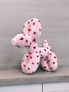 two pink knitted teddy bears sitting on top of a counter