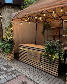 an outdoor stand with plants and lights on it