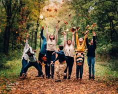 a group of people throwing leaves in the air while standing on a leaf covered road