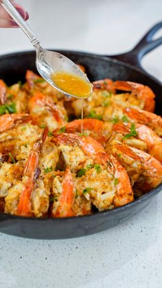 a pan filled with cooked shrimp being drizzled with sauce