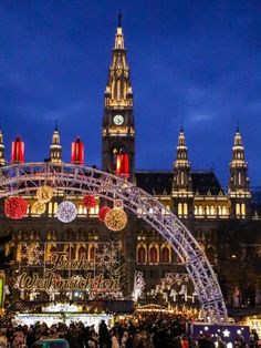 an outdoor christmas market in front of a large building with lights and decorations on it