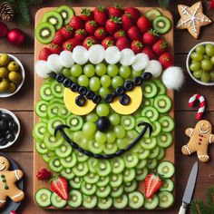 a platter filled with grapes, kiwis and strawberries in the shape of a face