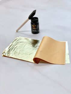 an open book sitting on top of a table next to a paintbrush and glue