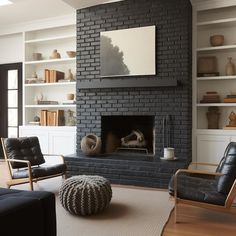 a living room filled with furniture and a fire place in front of a brick wall