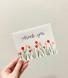 someone holding up a thank you card with red and orange tulips on it