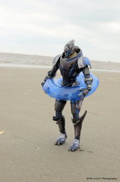 a man dressed in armor and holding a blue frisbee on the beach