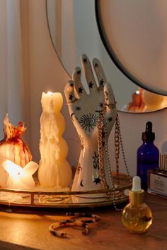 an assortment of candles on a tray with hand and star decorations in front of a mirror