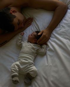 a man laying on top of a bed next to a baby