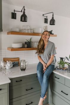 a woman sitting on top of a kitchen counter