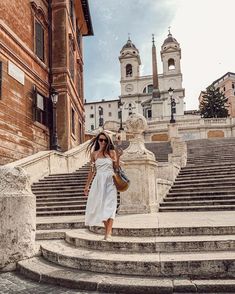 a woman is walking down some steps in front of an old building with steeples