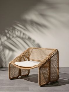 the chair is made out of wicker and has a white seat cushion on it