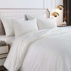 a bed with white sheets and pillows in a room