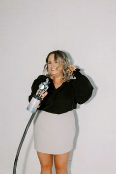 a woman is holding a vacuum cleaner and posing for the camera