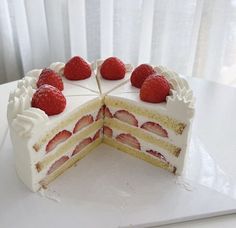 a cake with white frosting and strawberries on top is cut into four pieces