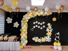 a table with balloons, cake and decorations on the wall in front of a black backdrop