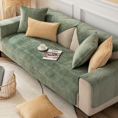 a green couch sitting on top of a hard wood floor next to a white rug