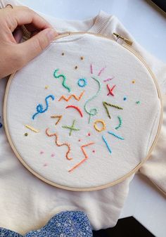 someone is stitching the numbers on a white t - shirt with colorful threads