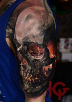 a man's arm with a skull and flames tattoo design on the upper half of his arm