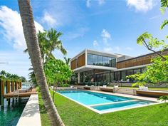 a large house with a swimming pool in front of it and palm trees on the other side