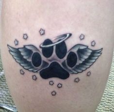 a dog's paw with an angel halo and stars tattoo on the leg,